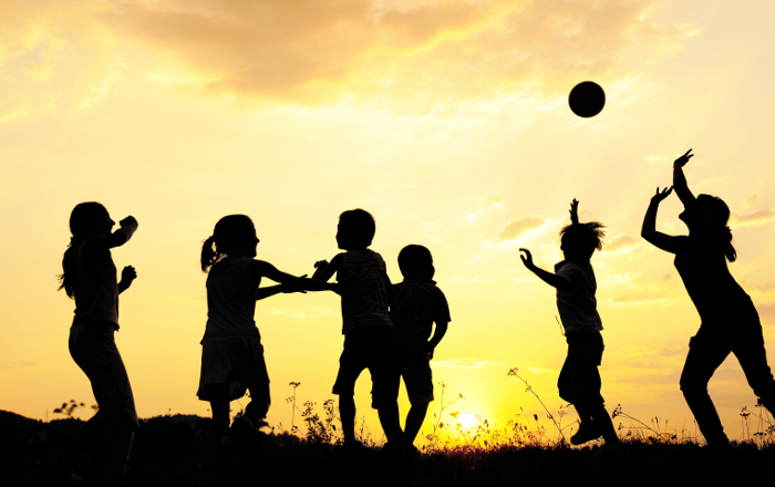 Silhouette, group of happy children playing on meadow, sunset, summertime